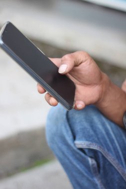 Ellerine odaklan. Endonezyalı bir adam iş için akıllı telefon tutuyor ve kullanıyor..