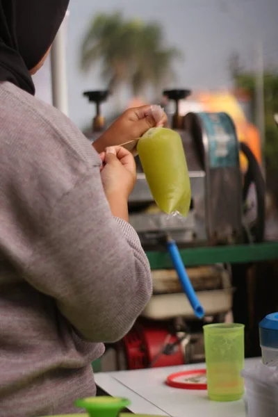 印尼街头摊贩手里拿着一杯甘蔗汁 — 图库照片