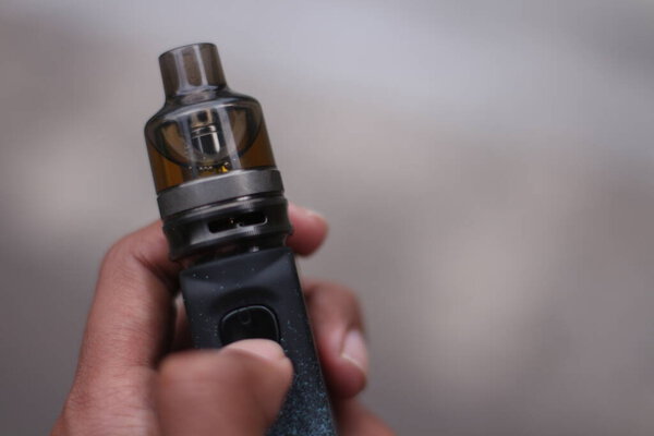 Man hand holding vape pen metal electronic cigarette with  blur background