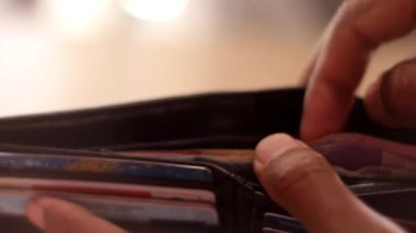 Elinde siyah bir cüzdan tutan bir adam Endonezya rupia banknotlarını öder..