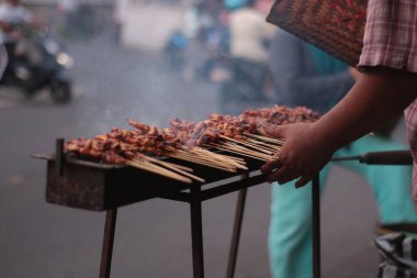 Geleneksel kömür üzerine tavuk satay. Satay dumanla ve iştah açıcı bir görüntüyle yanıyor. Eller ızgarada satay pişiriyor. İnsanlar zaten... 