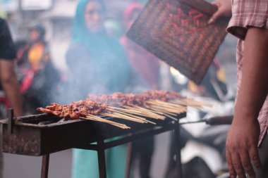 Geleneksel kömür üzerine tavuk satay. Satay dumanla ve iştah açıcı bir görüntüyle yanıyor. Eller ızgarada satay pişiriyor. İnsanlar zaten... 