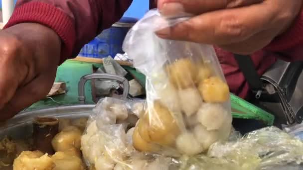 Siomayの売り手はプラスチック容器のバイヤーにサービスを提供しています Siomayはピーナッツソースと組み合わせた小麦粉と魚または鶏肉の混合物から作られた典型的なインドネシアのスナックです — ストック動画
