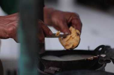 Açık pazarda krep yapmak. Bir elin dışarıda, metal bir tavada krep yapıyor..