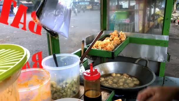 インドネシア人のストリートフードベンダーが屋外市場で顧客にサービスを提供しています ボロブドゥール通りの顧客に バディオール と呼ばれる料理を準備する男 — ストック動画
