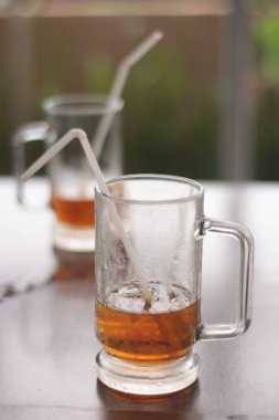 Bir restoranın ahşap masasında içilen soğuk çay içeceklerinin yakın çekimleri.