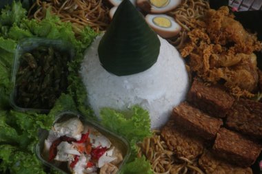 Nasi Tumpeng. Koni şeklinde sarı pirinç. Şenlikli bir Endonezya pirinç yemeği ve mezeler dini etkinliklerde servis edilir..