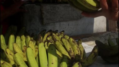 Endonezyalı adam yerel pazarda meyve ve sebze alışverişi yapıyor. Kadın marketten muz alıyor.