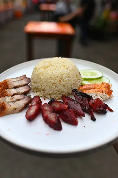 Rice on a white plate along with pork and duck