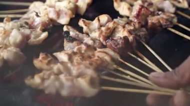 Tavuk satay kömürde kızartılıyor ve kenara çekiliyor, sokak yemeği.