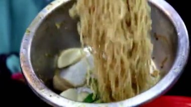 Erişteleri paslanmaz çelik bir kase ve sokak yemeğiyle karıştır.