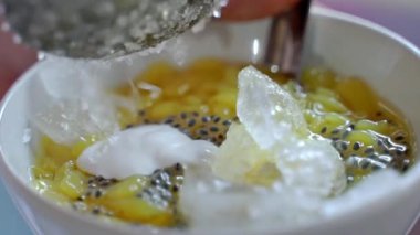 İçinde Cendol ve sokak yemekleri olan bir kaseye buz koymak.
