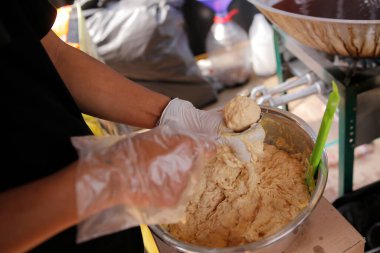 Bir şef köfteler için hamuru toplara dönüştürüyor ve hamur üzerinde yoğunlaşıyor.