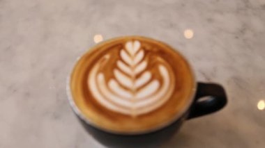 Siyah fincanda sütlü kahve ve mermer masada kahve.