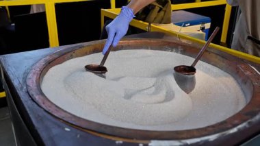 Eldivenli ve kaşıklı tencerenin içinde kahve var dışarıda kum var, Türk kahvesi. Yemek, mutfak, kafe, yaz, açık hava yemekleri, içecekler ve kahve konsepti için elverişli..