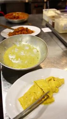 Beyaz tabak, sarı makarna ve İtalyan mutfağı hazırlayan şefin yemek çubukları. Yemek blogları, restoran menüleri, Asya mutfağı kavramları için uygundur..