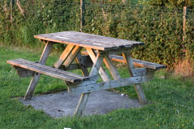 Tahta bank, masa ya da parkta piknik masası, çimen ya da bahçe. Yeşil çimenli parkta yemek için eski bir ahşap bank. Eski mobilyaları olan açık hava oturma alanı..