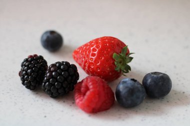 Karışık böğürtlen. Taze çilek, yabanmersini, ahududu, böğürtlen. Vitaminli sağlıklı diyet. Meyveleri renkli yiyeceklerle karıştır. Market malzemeleri, tarifler, kilo vermek için cilt bakımı..