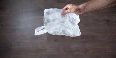Erkek eli, kahverengi arka plandaki polietilen çanta.