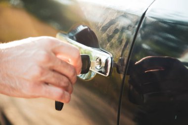  Adam caddenin anahtarlarında arabanın kapısını açıyor.