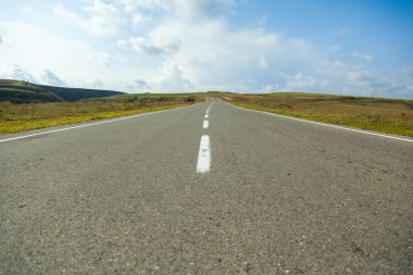 Mavi gökyüzünün altında asfalt yolu olan manzara