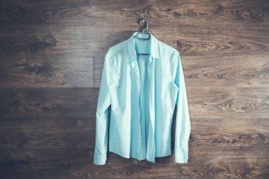 Koyu arkaplanda asılı mavi gömlekli adam.