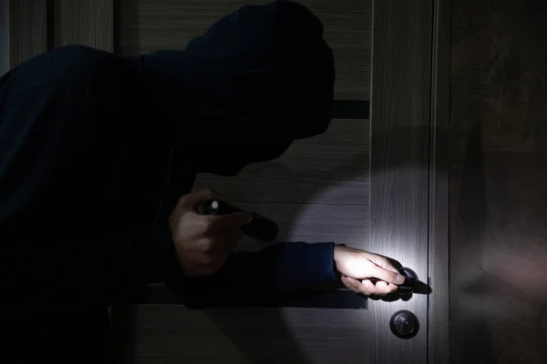 stock image man burglar sneaking into the house with flashligh