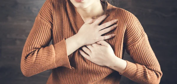 woman hand in ache heart on dark background
