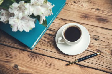 Kitapta çiçekler, masada kahve.