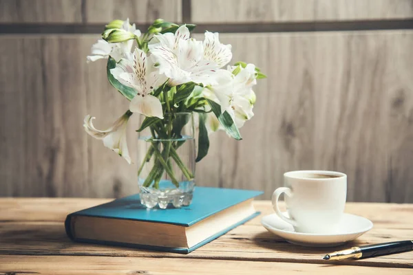 flowers on book  with coffee on desk