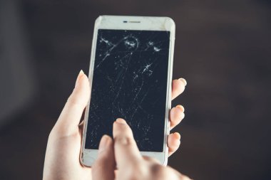 Kadın eli kırık, kahverengi arka planda akıllı telefon.