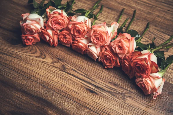 木制桌子背景上的粉红玫瑰 — 图库照片