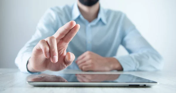 man hand tablet with finger in screen on table background