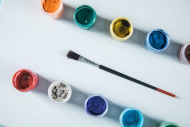 Masanın üzerinde bir kutu guaj ve fırça var.