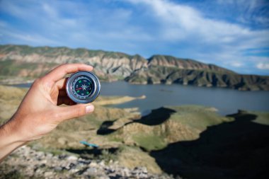 İnsan eli pusula ve dağ arka planında göl