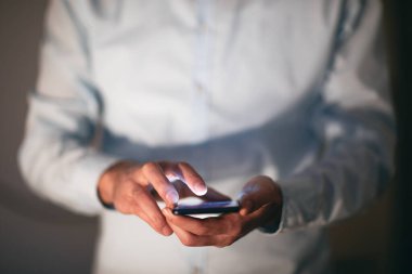 man hand smart phone on dark background