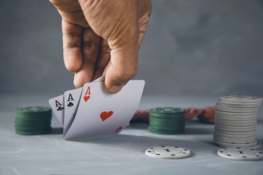 Adam gri arka planda poker oynuyor.