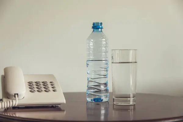 瓶装水和玻璃杯 桌上有电话 图库图片
