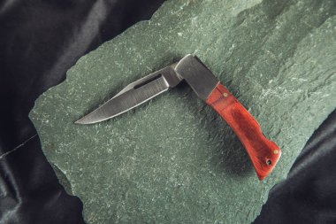 the pocket knife on the stone background clipart