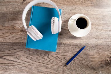 Kitapta kulaklık, sehpada kahve.