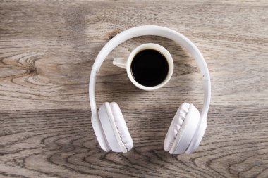 Kulaklıklı, sehpasında kahve olan.