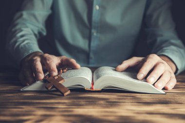 Dua eden adam kutsal İncil 'i ahşap masada çaprazladı.