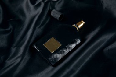 Siyah arka planda bir şişe parfüm.
