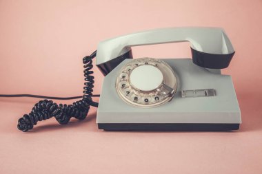 Pembe masa arkasında eski bir telefon var.