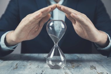 Masada kum saati olan genç bir iş adamı.