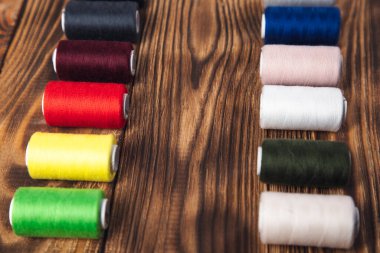 Ahşap arkaplanda renkli iplik makaraları.