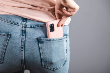 Kot pantolonun içinde akıllı telefonu tutan kadın.