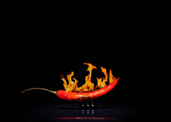 chili pepper on a fork in the fire, hot chili pepper close-up