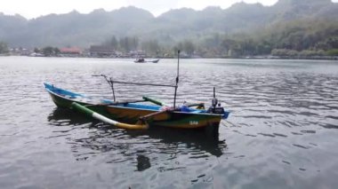 Kebumen, Central Java Endonezya 23 Temmuz 2023: Arka planda yeşil ağaçlar olan nehirde üç balıkçı teknesi