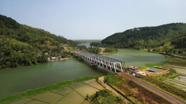 Dağ nehri ve ağaçlar manzaralı demiryolu köprüsünün hava aracı görüntüsü